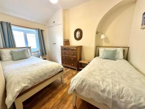 a bedroom with two beds and a clock on the wall at 3 Bed in Aberdyfi oc-dy024 in Aberdyfi