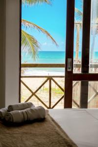 a bedroom with a view of the beach from a window at Pousada Maraca Beach in Porto De Galinhas