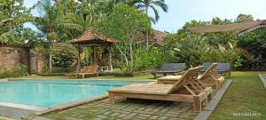 a pool with chairs and a table next to a house at Blauwtuin Yogyakarta in Yogyakarta