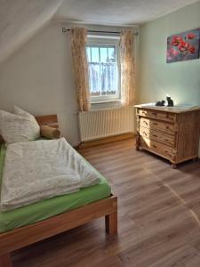 a bedroom with a bed and a dresser and a window at Dahoam am Silberberg in Bodenmais