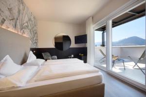 a bedroom with a large bed and a large window at Hotel Ladurner in Merano
