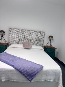 a white bed with a purple blanket and two lamps at ViLLA DANEIRA LUX in Mogán +14 photos