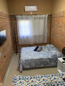 a bedroom with two beds and a brick wall at Casa Studio Uirá em Chapada dos Guimarães in Chapada dos Guimarães