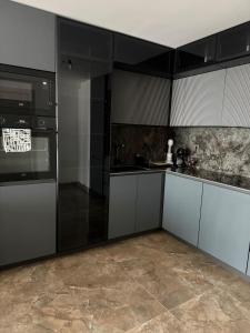 a kitchen with white cabinets and black appliances at Executive Sky Residence in Skopje