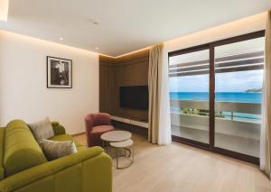 a living room with a green couch and a large window at Radisson Resort Ruza Vjetrova in Dobra Voda