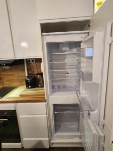 an empty refrigerator with its door open in a kitchen at Luxy Room in Courseulles-sur-Mer