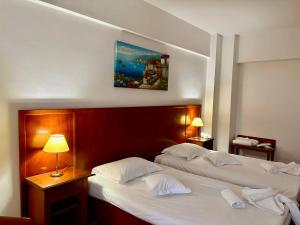 two beds in a hotel room with two lamps at Hotel Emma West in Craiova +106 photos