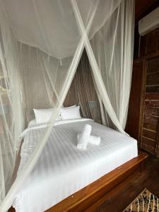 a white bed with two towels on top of it at Panoramic Samplik View Sidemen in Silebeng