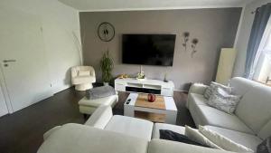 a living room with white furniture and a flat screen tv at Ferienwohnung am Chursbach in Callenberg
