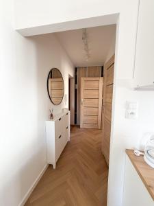 a kitchen with white walls and wood floors and a mirror at Jaśminowy Apartament in Sławno