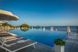 a pool with chairs and an umbrella and the ocean at La porta sul Mare - Apartment Punta in Veli Lošinj