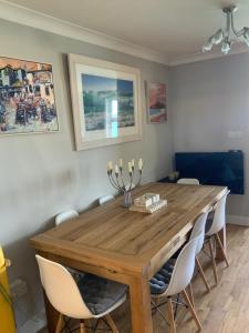 a dining room with a wooden table and white chairs at Aigua Blava in Carbis Bay +23 photos