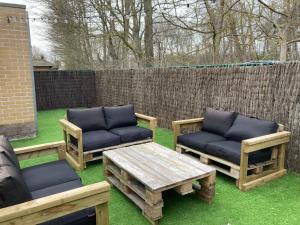 a backyard with two chairs and a coffee table and a fence at Boszicht 32 in De Haan