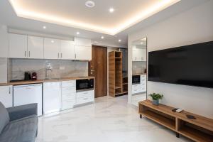 a kitchen with white cabinets and a large flat screen tv at OLYMPIADA GIRNI Suites in Paralia Katerinis
