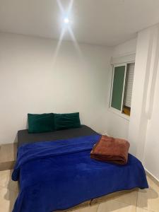 a bed in a white room with a blue blanket at Apparemment BAHRA in Taza