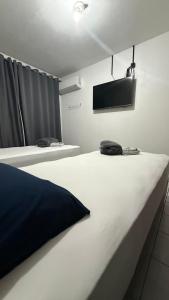 two beds in a room with a tv on the wall at Pousada Central Jaraguá in Jaraguá do Sul