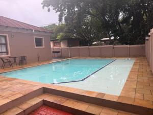 ein Swimmingpool im Garten mit Tisch und Stühlen in der Unterkunft Liquid Blue Guesthouse in Louis Trichardt