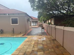 Ein Haus mit Swimmingpool neben einem Zaun in der Unterkunft Liquid Blue Guesthouse in Louis Trichardt