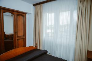 ein Schlafzimmer mit einem Bett und einem großen Fenster in der Unterkunft COM Home Tarnaveni - Free Parking - 24h Self check-in in Tîrnăveni + 4 Fotos