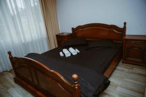 ein Schlafzimmer mit einem Holzbett und zwei weißen Pantoffeln in der Unterkunft COM Home Tarnaveni - Free Parking - 24h Self check-in in Tîrnăveni