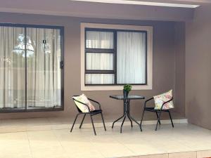 ein Zimmer mit zwei Stühlen, einem Tisch und zwei Fenstern in der Unterkunft Liquid Blue Guesthouse in Louis Trichardt