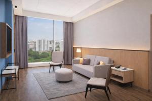 a living room with a couch and chairs and a large window at Four Points by Sheraton Nashik in Nashik