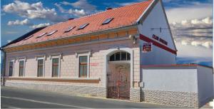a building with a red roof on a street at Szlavi Apartman in Baja