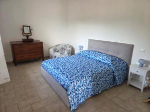 a bedroom with a bed with a blue comforter and a chair at Il Grottino di Sarzana in Sarzana