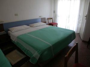 a green bed in a room with a window at Hotel Cristallo Cesenatico in Cesenatico