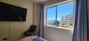 a bedroom with a window with a view of the ocean at Departamento en Playa Las Cadenas in Algarrobo