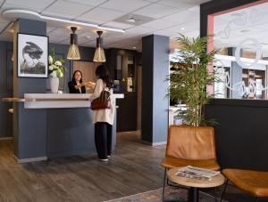 a woman standing at a counter in a salon at Oneloft Hotel in Obernai