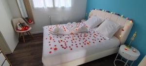 a bedroom with a white bed with red hearts on it at Île Dumet - Appt T2 cocooning - 2 à 4 pers. - Piscine & Spa in La Turballe