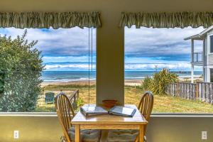 a table and chairs in a room with a view of the ocean at Inviting dog-friendly studio with unobstructed ocean views in Bandon