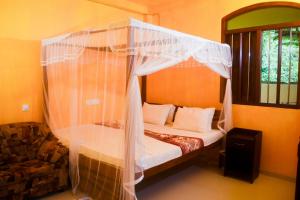 a bedroom with a canopy bed with white curtains at Villa Mihindi in Hikkaduwa