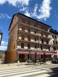 a building with tables and umbrellas in front of it at Hotel Pirineos Ainsa in Aínsa