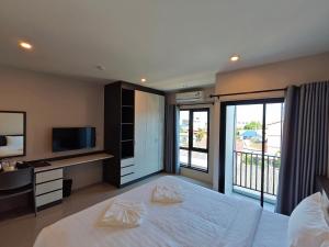 a bedroom with a bed with a television and a balcony at Prajan Residence in Buriram
