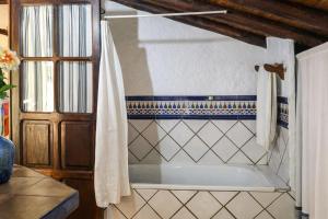 a bathroom with a tub with a shower curtain at Complejo El Alambique in Algatocín