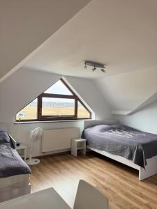 a attic bedroom with a bed and a window at TOBI-pokoje gościnne in Łeba