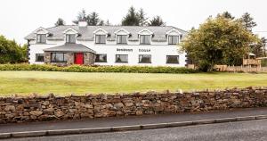 a large white house with a stone wall at Benbaun House in Clifden