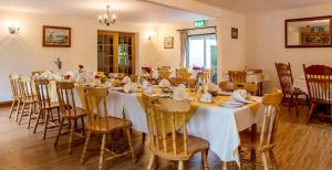 a room with a long table with white tables and chairs at Benbaun House in Clifden