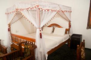 a bedroom with a canopy bed with white sheets and pillows at Villa Mihindi in Hikkaduwa