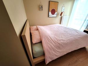a small bedroom with a bed with pink sheets at Appartement lumineux proche Genève et Jura 3 chambres, terrasses et parking in Gex