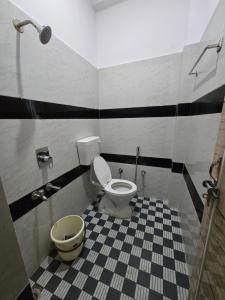 a bathroom with a white toilet and a checkered floor at Arctic Inn in Gorakhpur