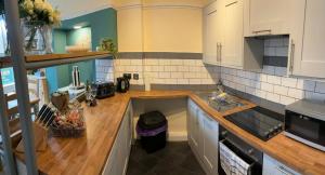 a kitchen with white cabinets and a wooden counter top at The Old Bakery in Sandwich +3 photos