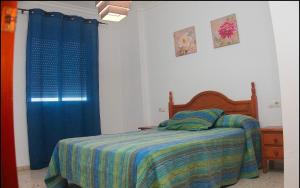 1 dormitorio con cama y cortina azul en Apartamento Centro Tonelero II, en Conil de la Frontera