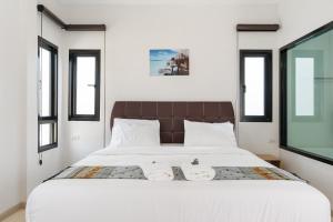 a bedroom with a large white bed with windows at Deluxe Hotel Chaiyaphum in Chaiyaphum