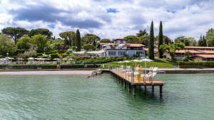 a dock with chairs and umbrellas on a body of water at Club del Sole Desenzano Boutique Resort in Desenzano del Garda