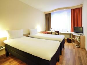 ein Hotelzimmer mit zwei Betten und einem Fernseher in der Unterkunft Ibis Budapest City in Budapest