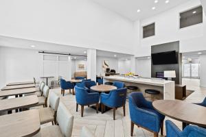 a lobby with blue chairs and tables and a tv at Staybridge Suites - Calgary Airport by IHG in Calgary