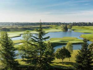 an aerial view of a golf course with a lake at Novotel Saint-Quentin en Yvelines in Magny-les-Hameaux
